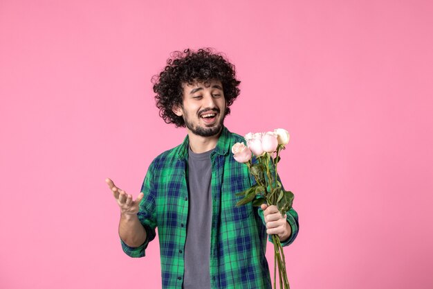 Jovem macho com rosas cor de rosa na frente