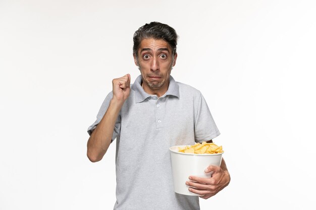 Jovem macho comendo batata frita assistindo filme em uma superfície branca