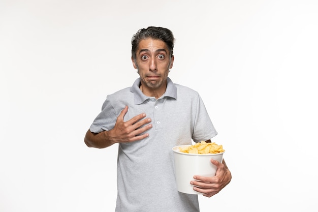 Jovem macho comendo batata frita assistindo filme na superfície branca