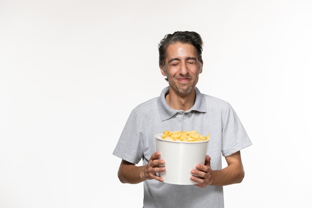 Jovem macho comendo batata frita na mesa branca