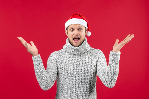 Jovem macho de camisa quente com tampa de natal e fundo vermelho.