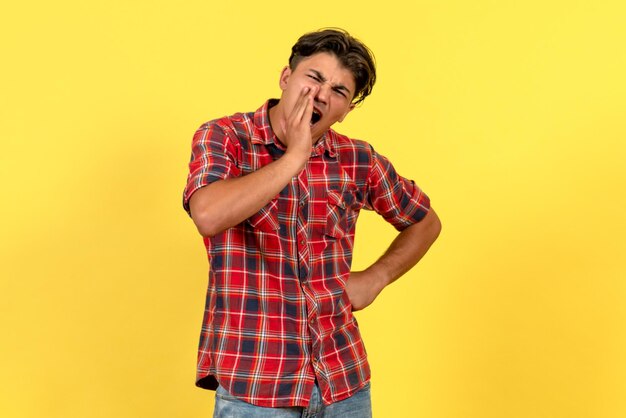 Jovem macho gritando de frente no fundo amarelo