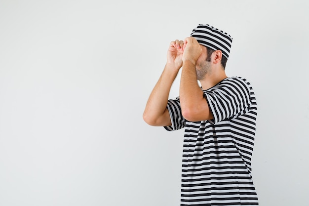 Foto grátis jovem macho mostrando gesto de óculos em t-shirt, chapéu e olhando focado.