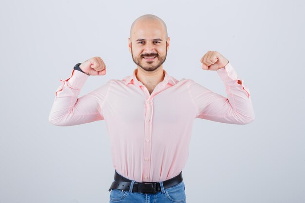 Jovem macho mostrando gesto de vencedor em camiseta, jeans e parecendo com sorte. vista frontal.