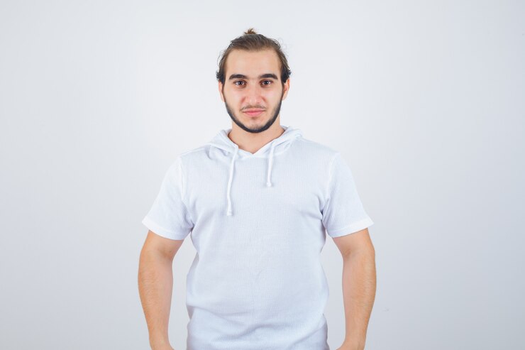 Foto grátis jovem macho olhando para a câmera no moletom com capuz e parecendo confiante, vista frontal.