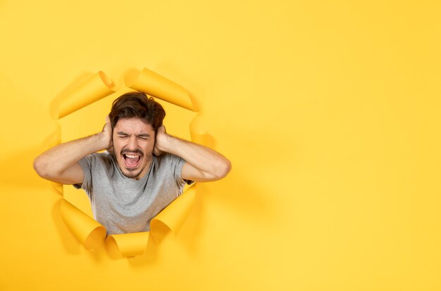 Jovem macho pensando e olhando de fundo de papel amarelo rasgado rosto interno