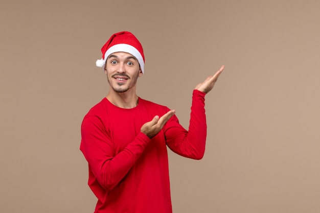 Jovem macho posando com rosto animado em emoções de fundo marrom feriado natal