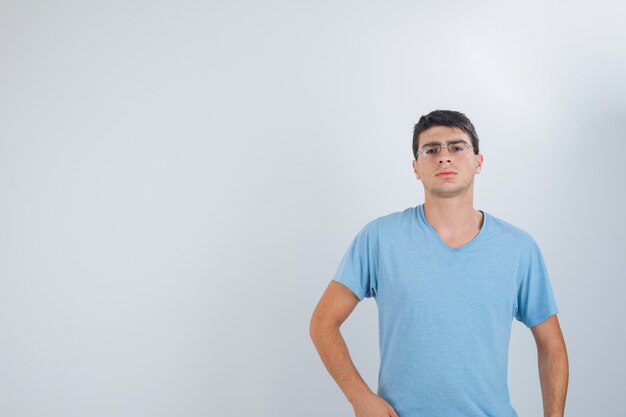 Jovem macho posando enquanto olha para a câmera em t-shirt e olhando sério, vista frontal.