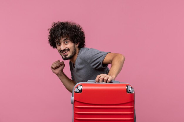 Jovem macho saindo de férias com sua bolsa vermelha no espaço rosa