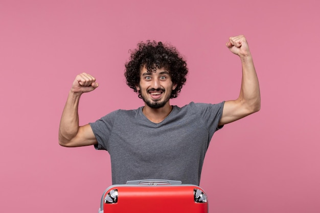 Jovem macho saindo de férias com sua bolsa vermelha se sentindo feliz no espaço rosa