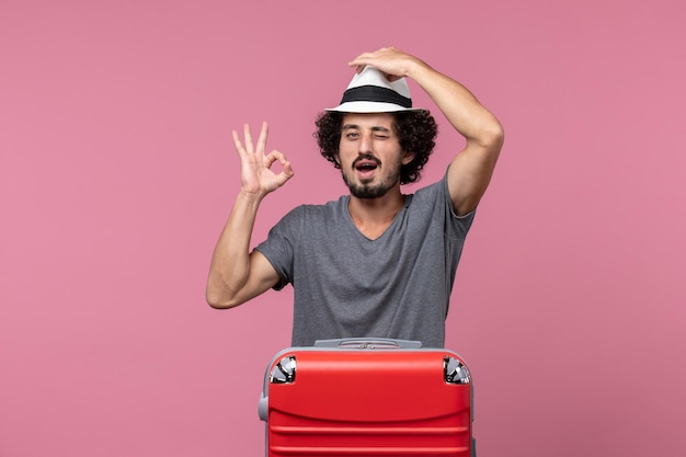 Jovem macho se preparando para as férias com chapéu no espaço rosa