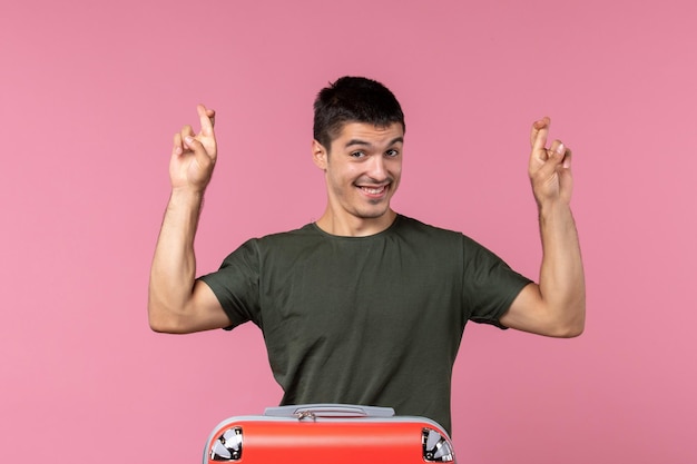 Foto grátis jovem macho se preparando para as férias cruzando os dedos no espaço rosa