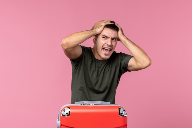 Jovem macho se preparando para uma viagem segurando a cabeça no espaço rosa