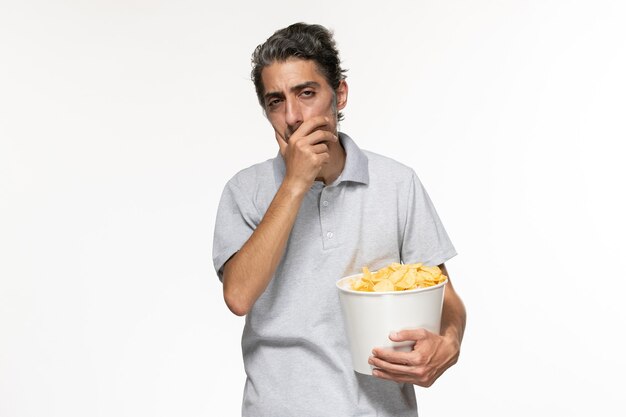 Jovem macho segurando a cesta com batata frita e pensando na superfície branca