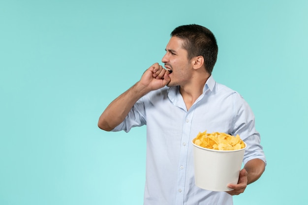 Jovem macho comendo batata frita assistindo filme na superfície branca