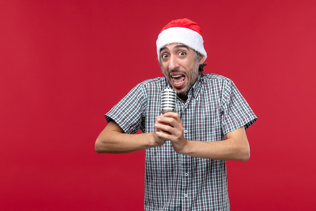 Foto grátis jovem macho segurando o microfone no fundo vermelho