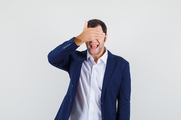 Jovem macho segurando os olhos com a mão na camisa