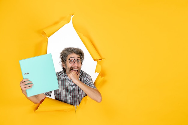 Jovem macho segurando um arquivo verde sobre fundo amarelo cor de fundo amarelo trabalho escritório emoção férias trabalho