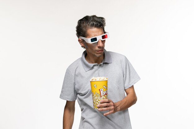 Jovem macho segurando um pacote de pipoca em óculos de sol na superfície branca