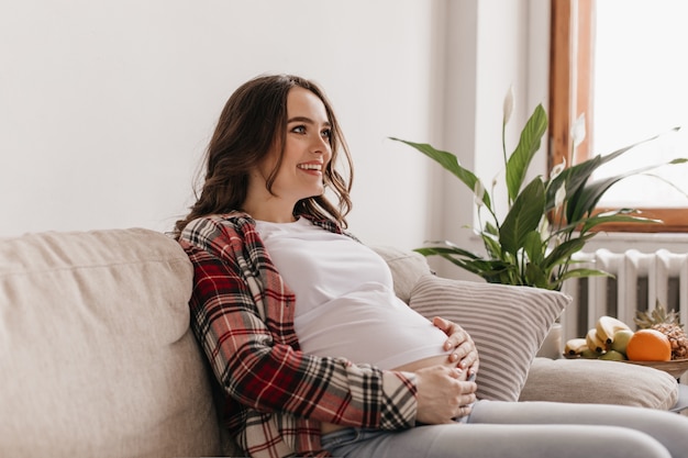 Jovem mãe alegre e feliz sorrindo e relaxando no sofá