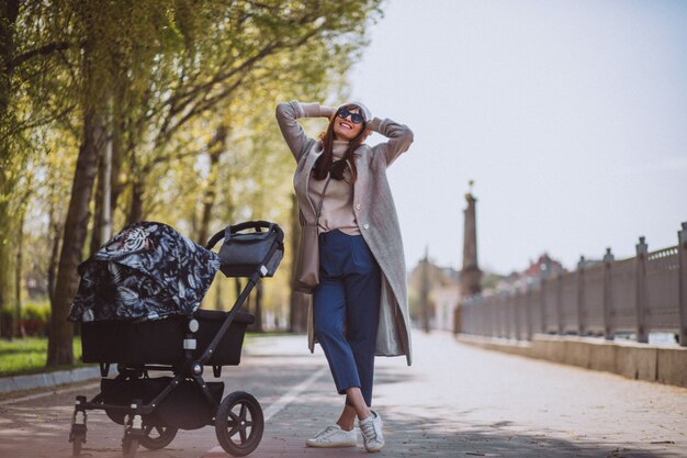 Jovem mãe andando com carrinho de bebê no parque