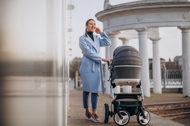 Jovem mãe andando com carrinho de bebê no parque