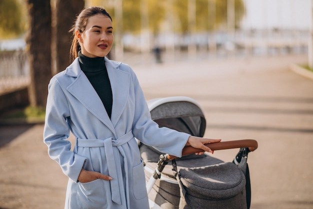 Jovem mãe andando com carrinho de bebê no parque