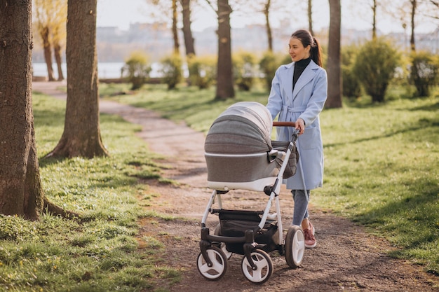 Jovem mãe andando com carrinho de bebê no parque