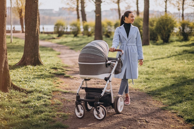 Jovem mãe andando com carrinho de bebê no parque