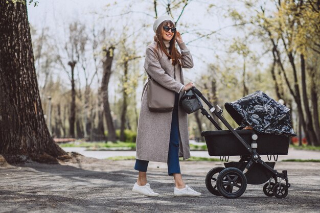 Jovem mãe andando com carrinho de bebê no parque