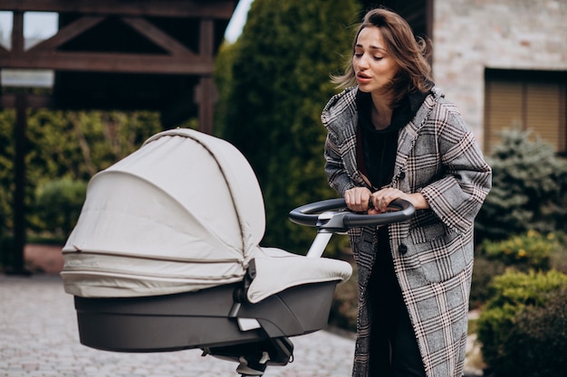 Jovem mãe andando com carrinho de bebê no parque