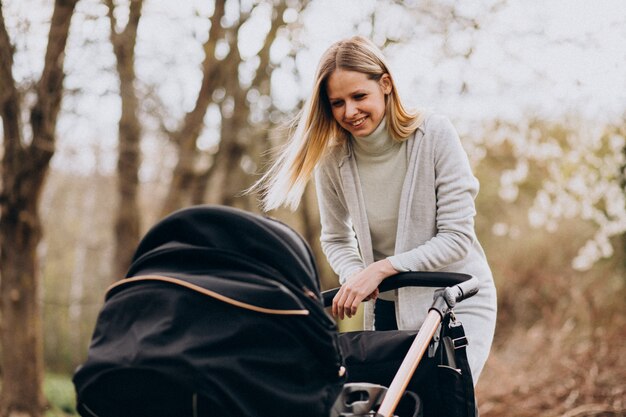 Jovem mãe andando com carrinho de bebê no parque