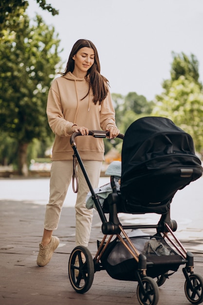 Jovem mãe andando com carrinho de bebê no parque