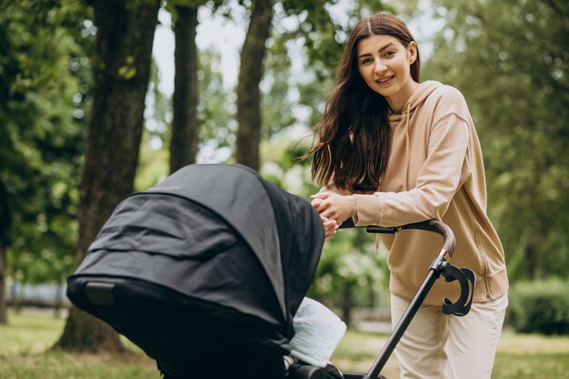 Jovem mãe andando com carrinho de bebê no parque