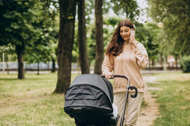 Jovem mãe andando com carrinho de bebê no parque