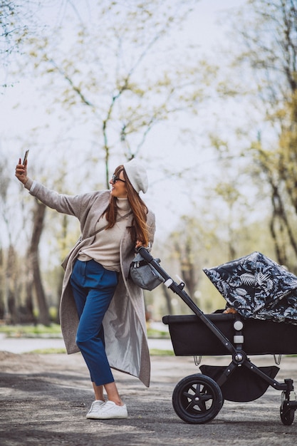 Jovem mãe caminhando com carrinho de bebê no parque