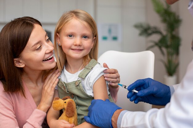 Jovem mãe com a filha no pediatra para tomar vacina