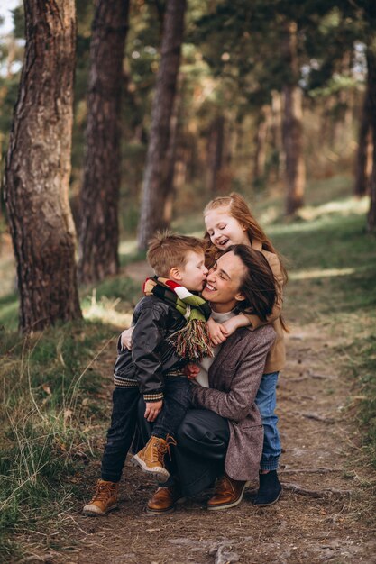 Jovem mãe com filha e filho na floresta