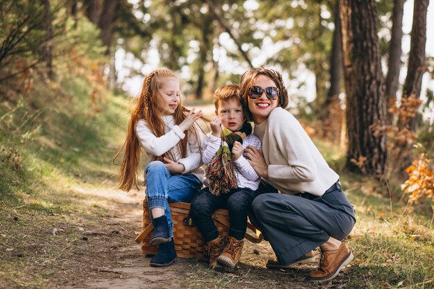 Jovem mãe com filha e filho na floresta