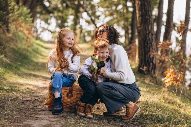 Jovem mãe com filha e filho na floresta