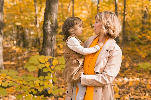 Jovem mãe com sua filha em um conceito de paternidade e filhos no parque outono outono