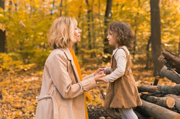 Jovem mãe com sua filha em um conceito de paternidade e filhos no parque outono outono