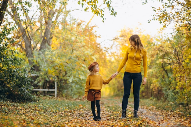Jovem mãe com sua filha em um parque de outono