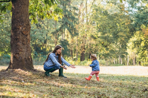 Jovem mãe com sua filha em um parque de outono