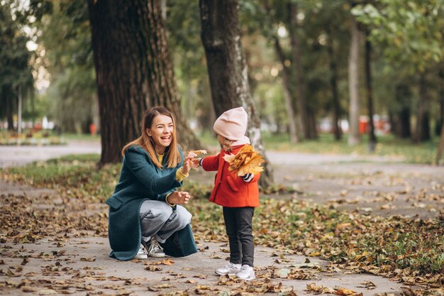 Jovem mãe com sua filha em um parque de outono