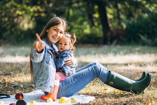 Jovem mãe com sua filha em um parque outono fazendo piquenique