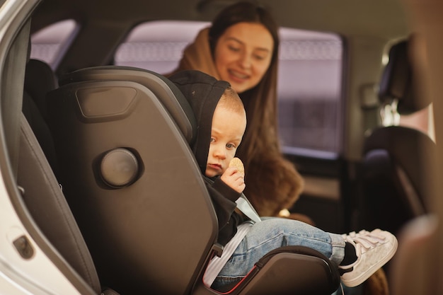 Jovem mãe e filho no carro Assento de bebê na cadeira Conceito de condução de segurança