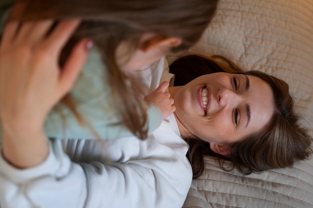 Foto grátis jovem mãe fazendo sua filha rir fazendo cócegas nela