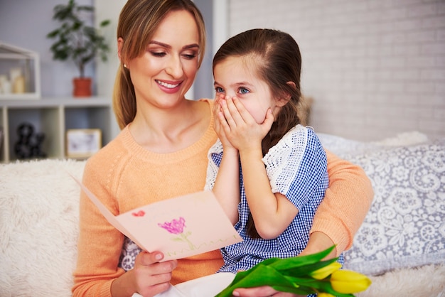 Jovem mãe lendo cartão de felicitações para o dia das mães