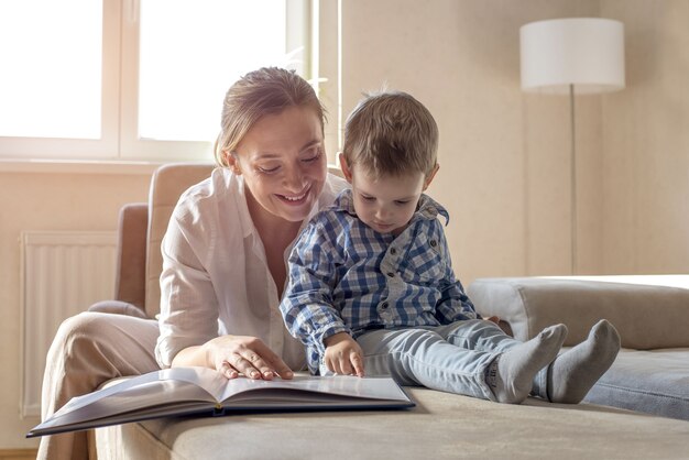 Jovem mãe lendo um livro para o filho de camisa azul